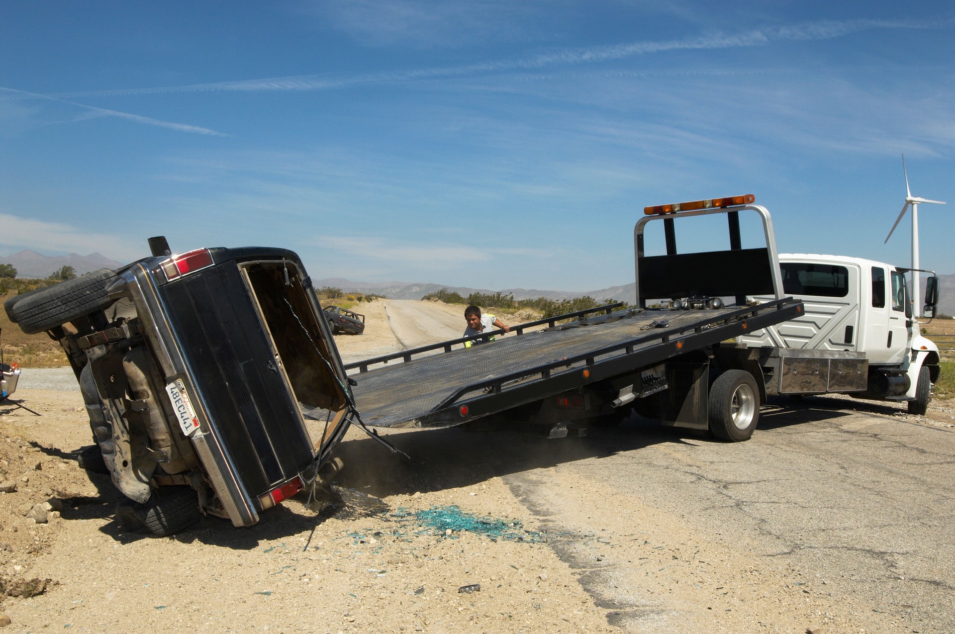 Man preparing to lift crashed car onto tow truck